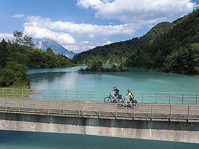 Cyclists on the bridge on the lake of Verzegnis