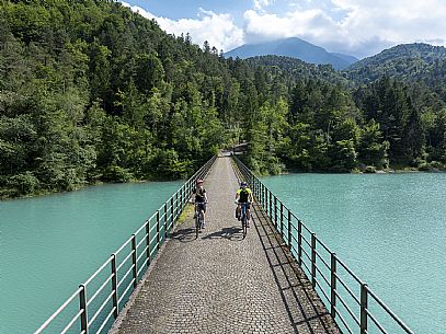Cyclists on the bridge on the lake of Verzegnis