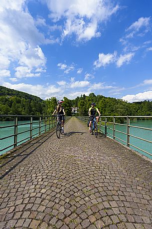 Cyclists on the bridge on the lake of Verzegnis