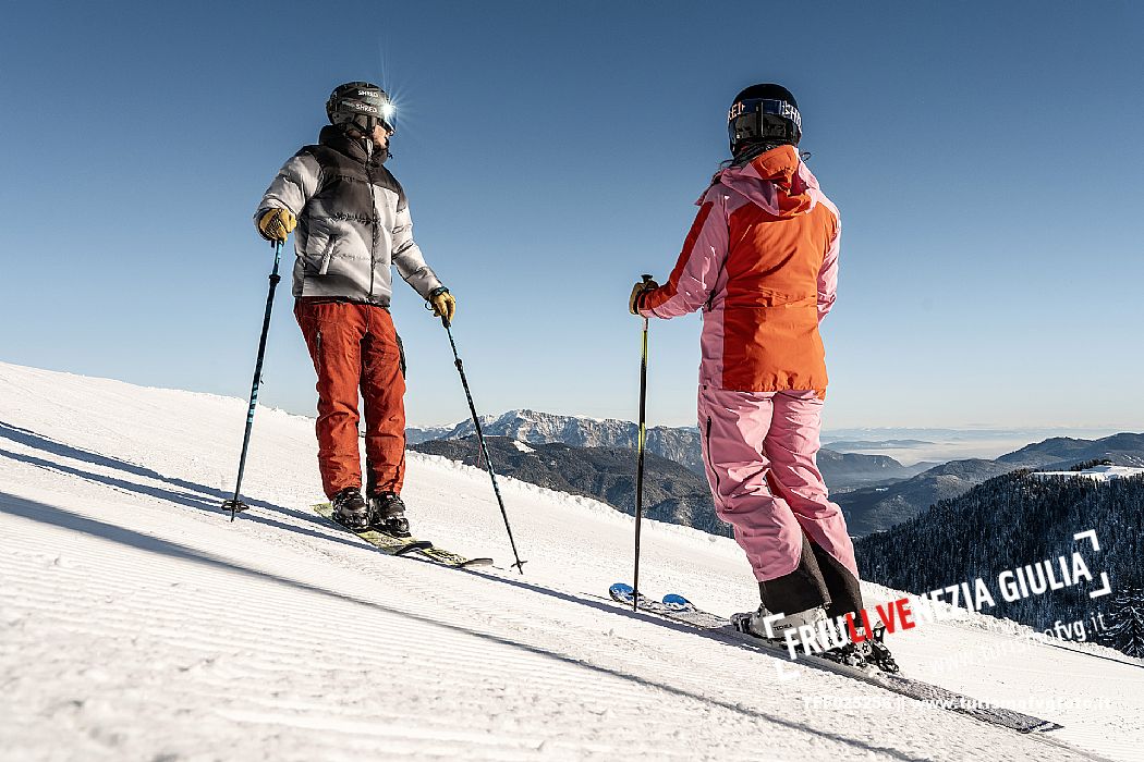 Alpine ski wit two skiers. Di Prampero slope on Lussari Mount.