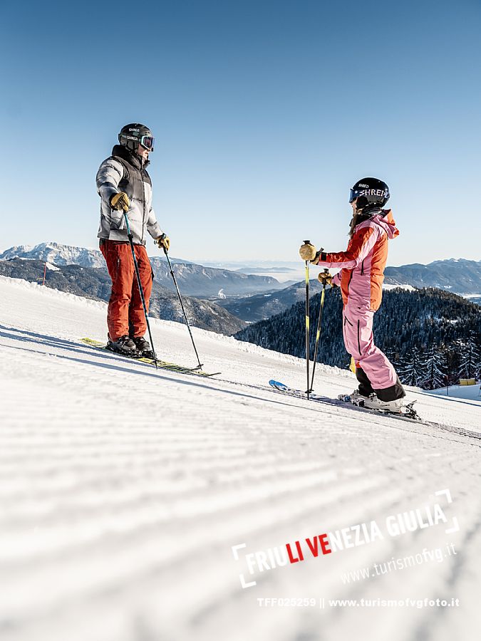 Alpine ski wit two skiers. Di Prampero slope on Lussari Mount.