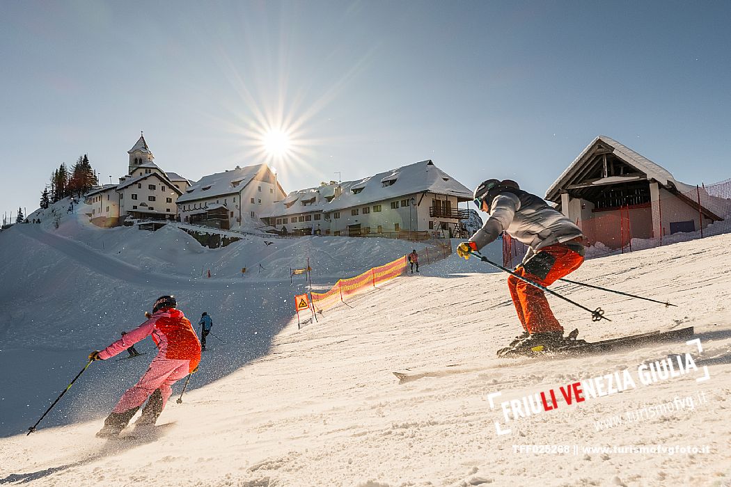 Alpine ski action wit two skiers. Di Prampero slope on Lussari Mount.