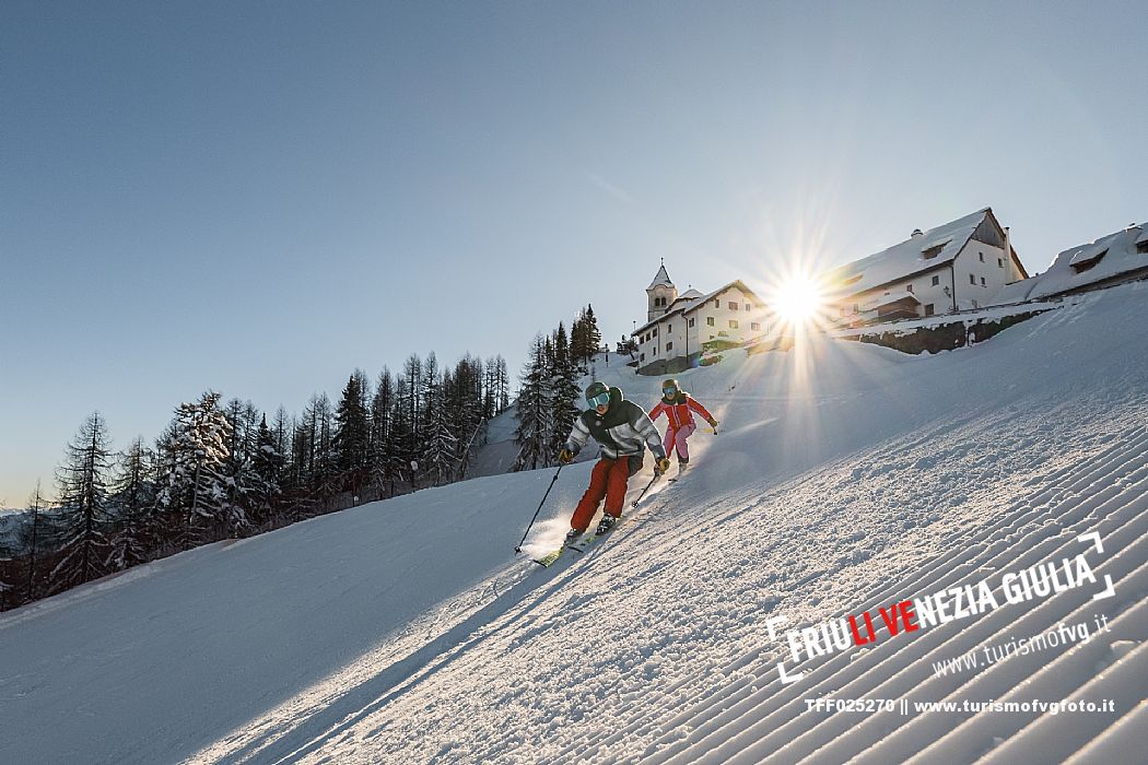 Alpine ski action wit two skiers. Di Prampero slope on Lussari Mount.