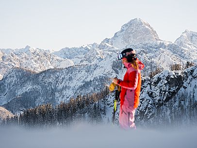 Alpine ski with joung skier woman. Di Prampero slope on Lussari Mount.