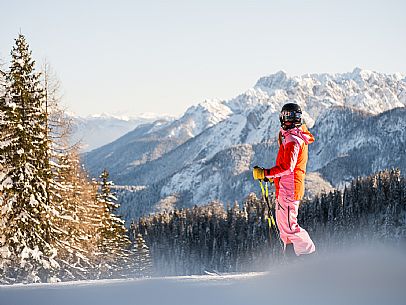 Alpine ski with joung skier woman. Di Prampero slope on Lussari Mount.