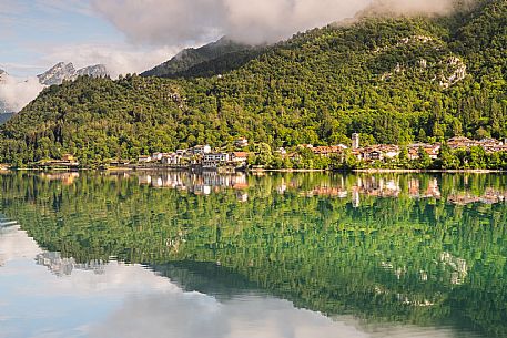 Barcis and its enchanting lake, on a sunny summer morning. In the background the peaks of the Cavallo group and the Friulian Dolomites.