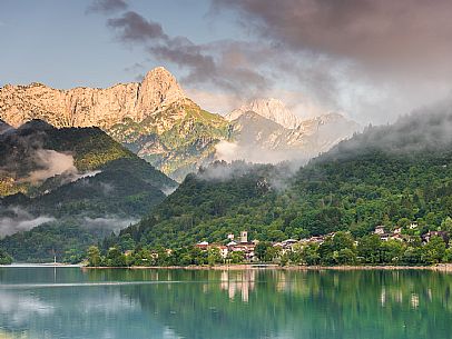 Barcis and its enchanting lake, on a sunny summer morning. In the background the peaks of the Cavallo group and the Friulian Dolomites.