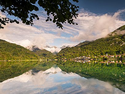 Barcis and its enchanting lake, on a sunny summer morning. In the background the peaks of the Cavallo group and the Friulian Dolomites.