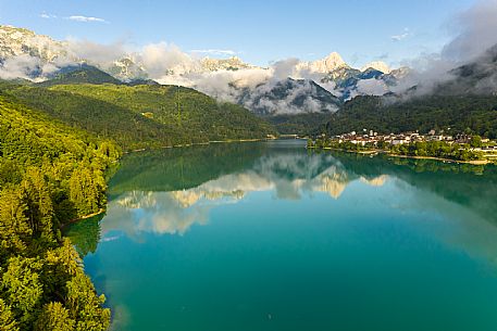 Barcis and its enchanting lake, on a sunny summer morning. In the background the peaks of the Cavallo group and the Friulian Dolomites.