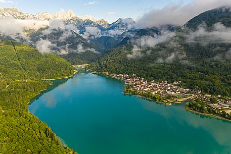 Barcis and its enchanting lake, on a sunny summer morning. In the background the peaks of the Cavallo group and the Friulian Dolomites.