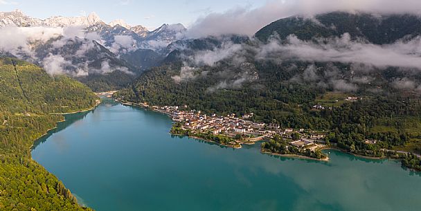 Barcis and its enchanting lake, on a sunny summer morning. In the background the peaks of the Cavallo group and the Friulian Dolomites.