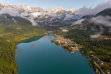 Barcis and its enchanting lake, on a sunny summer morning. In the background the peaks of the Cavallo group and the Friulian Dolomites.