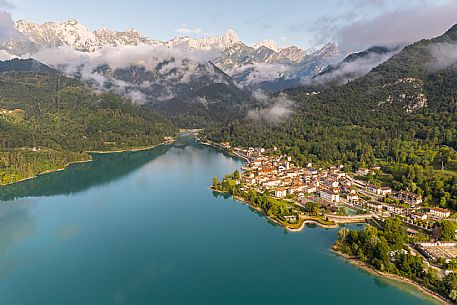 Barcis and its enchanting lake, on a sunny summer morning. In the background the peaks of the Cavallo group and the Friulian Dolomites.