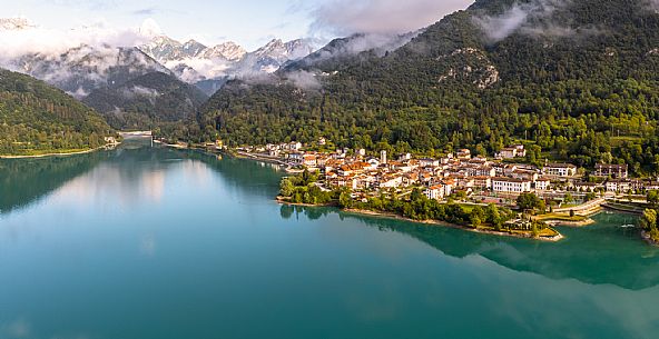 Barcis and its enchanting lake, on a sunny summer morning. In the background the peaks of the Cavallo group and the Friulian Dolomites.