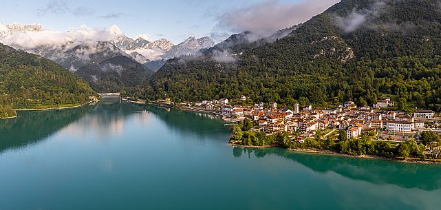 Barcis and its enchanting lake, on a sunny summer morning. In the background the peaks of the Cavallo group and the Friulian Dolomites.