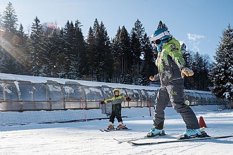 Teacher young woman and child learning alpine skiing in a school camp in Tarvisio.