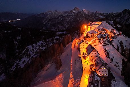 Night view of Monte Santo di Lussari, Italy, with illuminated buildings and a snowy slope. The Di Prampero slope in Camporosso welcomed the new year with the longest torchlight procession in the entire Alpine arc. Night view of Monte Santo di Lussari, Italy, with illuminated buildings and a snowy slope. The Di Prampero slope in Camporosso welcomed the new year with the longest torchlight procession in the entire Alpine arc.
