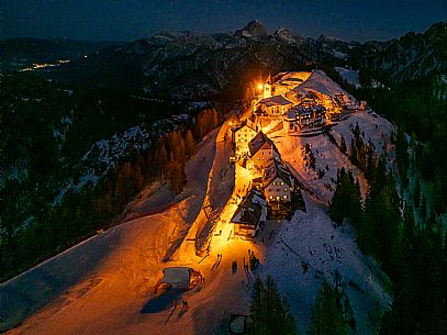 Night view of Monte Santo di Lussari, Italy, with illuminated buildings and a snowy slope. The Di Prampero slope in Camporosso welcomed the new year with the longest torchlight procession in the entire Alpine arc. Night view of Monte Santo di Lussari, Italy, with illuminated buildings and a snowy slope. The Di Prampero slope in Camporosso welcomed the new year with the longest torchlight procession in the entire Alpine arc.