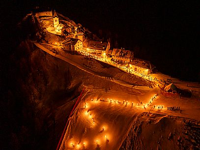 Night view of Monte Santo di Lussari, Italy, with illuminated buildings and a snowy slope. The Di Prampero slope in Camporosso welcomed the new year with the longest torchlight procession in the entire Alpine arc. Night view of Monte Santo di Lussari, Italy, with illuminated buildings and a snowy slope. The Di Prampero slope in Camporosso welcomed the new year with the longest torchlight procession in the entire Alpine arc.