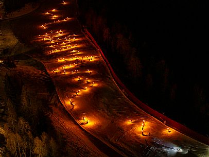 Night view of Monte Santo di Lussari, Italy, with illuminated buildings and a snowy slope. The Di Prampero slope in Camporosso welcomed the new year with the longest torchlight procession in the entire Alpine arc. Night view of Monte Santo di Lussari, Italy, with illuminated buildings and a snowy slope. The Di Prampero slope in Camporosso welcomed the new year with the longest torchlight procession in the entire Alpine arc.