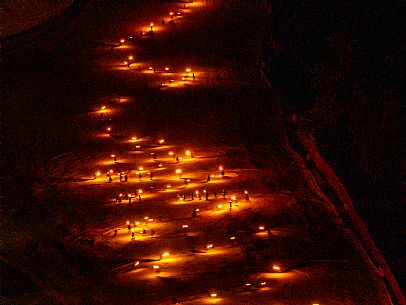 Night view of Monte Santo di Lussari, Italy, with illuminated buildings and a snowy slope. The Di Prampero slope in Camporosso welcomed the new year with the longest torchlight procession in the entire Alpine arc. Night view of Monte Santo di Lussari, Italy, with illuminated buildings and a snowy slope. The Di Prampero slope in Camporosso welcomed the new year with the longest torchlight procession in the entire Alpine arc.