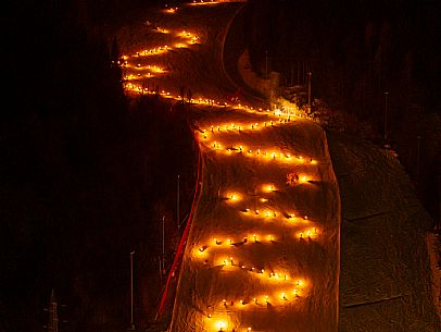 Night view of Monte Santo di Lussari, Italy, with illuminated buildings and a snowy slope. The Di Prampero slope in Camporosso welcomed the new year with the longest torchlight procession in the entire Alpine arc. Night view of Monte Santo di Lussari, Italy, with illuminated buildings and a snowy slope. The Di Prampero slope in Camporosso welcomed the new year with the longest torchlight procession in the entire Alpine arc.