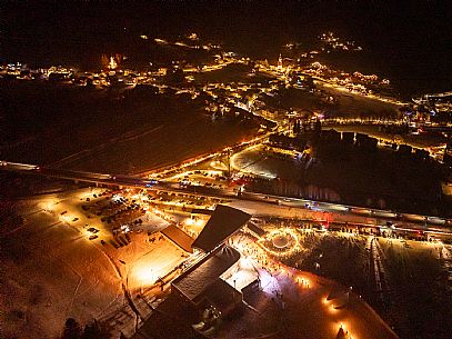 Night view of Monte Santo di Lussari, Italy, with illuminated buildings and a snowy slope. The Di Prampero slope in Camporosso welcomed the new year with the longest torchlight procession in the entire Alpine arc. Night view of Monte Santo di Lussari, Italy, with illuminated buildings and a snowy slope. The Di Prampero slope in Camporosso welcomed the new year with the longest torchlight procession in the entire Alpine arc.
