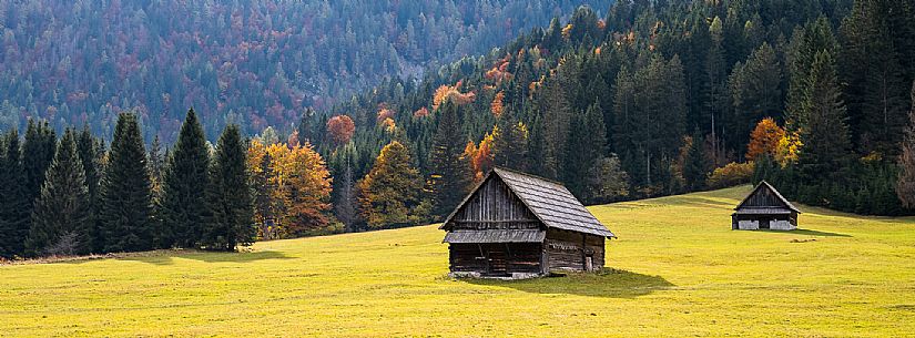 The meadows of Val Bartolo. Here you can immerse yourself in greenery, an expanse of meadows dotted with traditional mountain huts, characterised by wood and sloping roofs with balconies adorned with flowers. Landscapes and trekking in autumn.