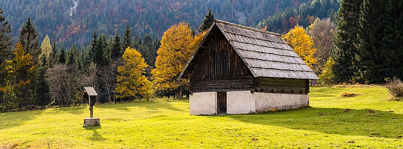 The meadows of Val Bartolo. Here you can immerse yourself in greenery, an expanse of meadows dotted with traditional mountain huts, characterised by wood and sloping roofs with balconies adorned with flowers. Landscapes and trekking in autumn.
