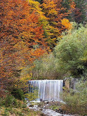 The meadows of Val Bartolo. Here you can immerse yourself in greenery, an expanse of meadows dotted with traditional mountain huts, characterised by wood and sloping roofs with balconies adorned with flowers. Landscapes and trekking in autumn.