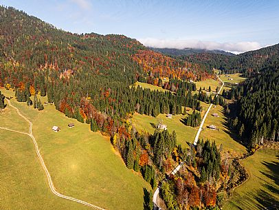 The meadows of Val Bartolo. Here you can immerse yourself in greenery, an expanse of meadows dotted with traditional mountain huts, characterised by wood and sloping roofs with balconies adorned with flowers. Landscapes and trekking in autumn.