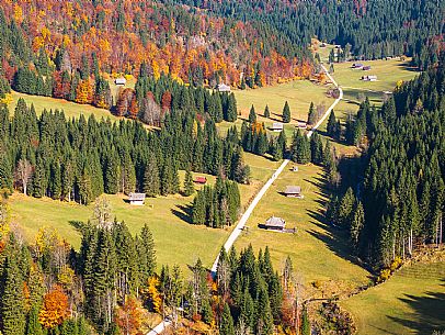 The meadows of Val Bartolo. Here you can immerse yourself in greenery, an expanse of meadows dotted with traditional mountain huts, characterised by wood and sloping roofs with balconies adorned with flowers. Landscapes and trekking in autumn.