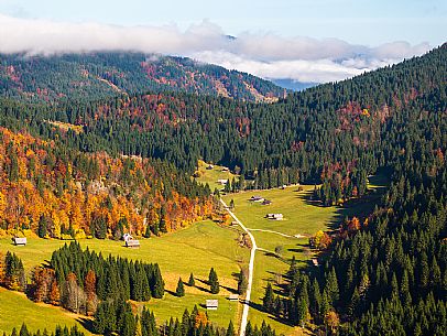 The meadows of Val Bartolo. Here you can immerse yourself in greenery, an expanse of meadows dotted with traditional mountain huts, characterised by wood and sloping roofs with balconies adorned with flowers. Landscapes and trekking in autumn.