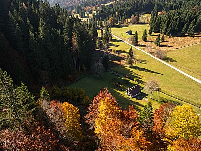 The meadows of Val Bartolo. Here you can immerse yourself in greenery, an expanse of meadows dotted with traditional mountain huts, characterised by wood and sloping roofs with balconies adorned with flowers. Landscapes and trekking in autumn.