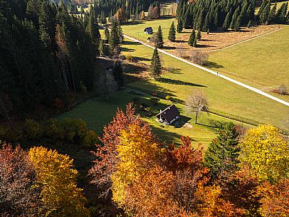 The meadows of Val Bartolo. Here you can immerse yourself in greenery, an expanse of meadows dotted with traditional mountain huts, characterised by wood and sloping roofs with balconies adorned with flowers. Landscapes and trekking in autumn.
