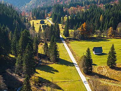The meadows of Val Bartolo. Here you can immerse yourself in greenery, an expanse of meadows dotted with traditional mountain huts, characterised by wood and sloping roofs with balconies adorned with flowers. Landscapes and trekking in autumn.