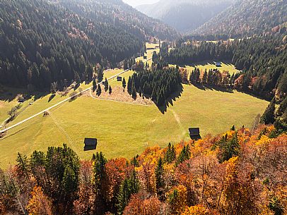 The meadows of Val Bartolo. Here you can immerse yourself in greenery, an expanse of meadows dotted with traditional mountain huts, characterised by wood and sloping roofs with balconies adorned with flowers. Landscapes and trekking in autumn.