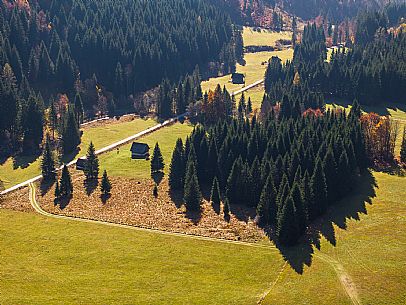 The meadows of Val Bartolo. Here you can immerse yourself in greenery, an expanse of meadows dotted with traditional mountain huts, characterised by wood and sloping roofs with balconies adorned with flowers. Landscapes and trekking in autumn.