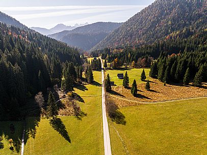 The meadows of Val Bartolo. Here you can immerse yourself in greenery, an expanse of meadows dotted with traditional mountain huts, characterised by wood and sloping roofs with balconies adorned with flowers. Landscapes and trekking in autumn.