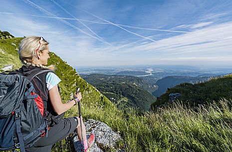 Mount Cuar, Friuli Venezia Giulia, Italy. Young hiker along the summit ridge connecting Cuel dai Poz to the summit of Mount Cuar, with a panoramic view overlooking the Friulian Plain and the surrounding landscape. [IT] Monte Cuar, Friuli Venezia Giulia, Italia. Giovane escursionista lungo la cresta sommitale che collega il Cuel dai Poz alla vetta del Monte Cuar, con vista panoramica sulla pianura friulana e sul paesaggio circostante.
