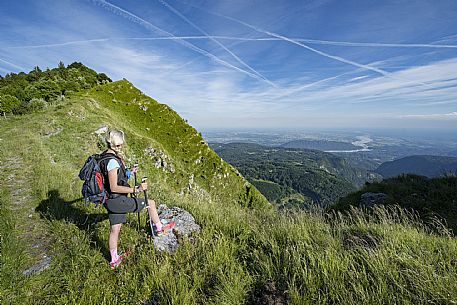 Mount Cuar, Friuli Venezia Giulia, Italy. Young hiker along the summit ridge connecting Cuel dai Poz to the summit of Mount Cuar, with a panoramic view overlooking the Friulian Plain and the surrounding landscape. [IT] Monte Cuar, Friuli Venezia Giulia, Italia. Giovane escursionista lungo la cresta sommitale che collega il Cuel dai Poz alla vetta del Monte Cuar, con vista panoramica sulla pianura friulana e sul paesaggio circostante.