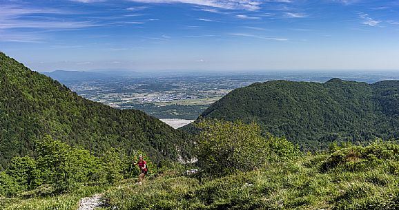 Mount Cuar, Friuli Venezia Giulia, Italy. Young hiker along the summit ridge connecting Cuel dai Poz to the summit of Mount Cuar, with a panoramic view overlooking the Friulian Plain and the surrounding landscape. [IT] Monte Cuar, Friuli Venezia Giulia, Italia. Giovane escursionista lungo la cresta sommitale che collega il Cuel dai Poz alla vetta del Monte Cuar, con vista panoramica sulla pianura friulana e sul paesaggio circostante.