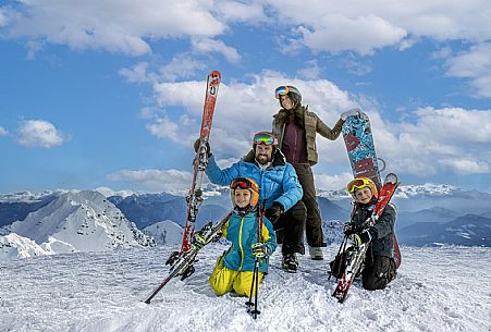 A couple with children wearing winter ski clothing on the slopes of the Zoncolan ski area, Carnia, Friuli Venezia Giulia, Italy.
